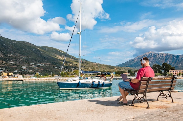 Man freelancer working on laptop at city harbor bench summertime