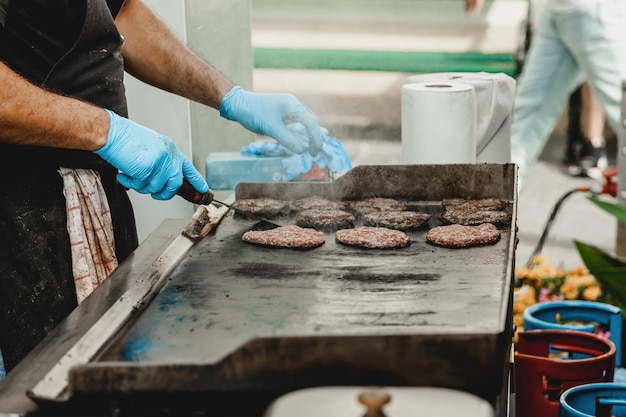Un uomo frigge polpette di hamburger uomo griglia una specie di carne marinata sulla griglia a gas durante l'estate