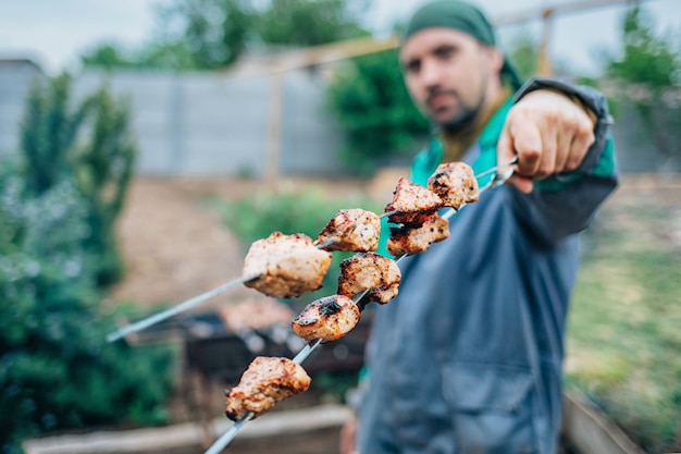 Photo man fries kebab on the grill