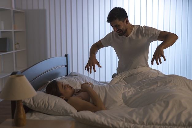 Мужчина пугает женщину в постели