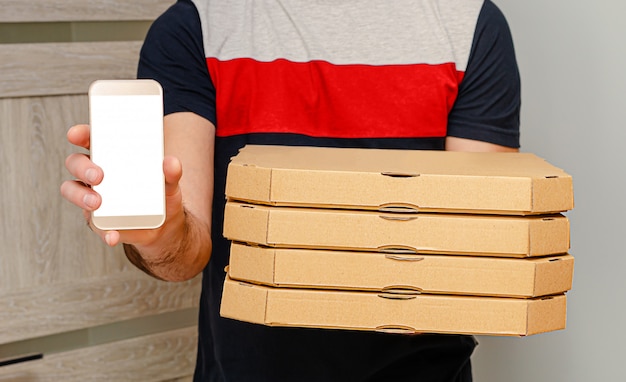 Foto uomo dal servizio di consegna che tiene le scatole e lo smartphone della pizza con derisione su. ordine alimentare su internet.