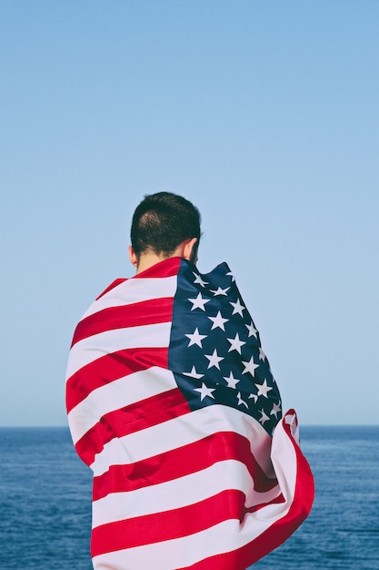 Man from behind wrapped in American Flag