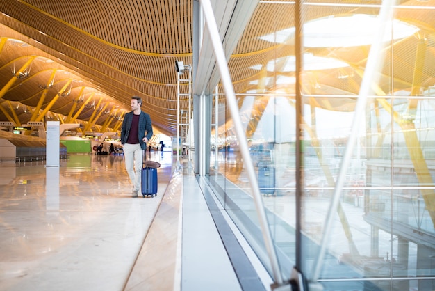 Man front walking at the airport using mobile phone