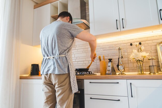 キッチン料理のコンセプトで鍋で揚げる男