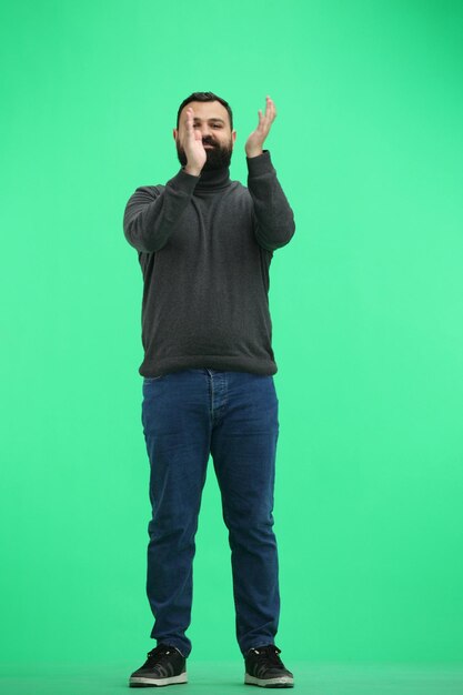 Photo a man fulllength on a green background claps