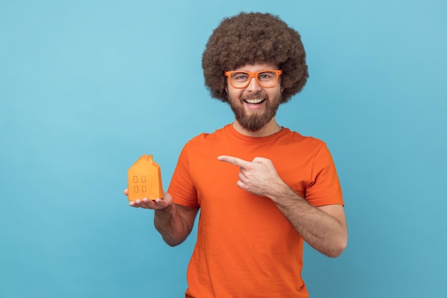 Man in funny eyeglasses holding pointing at paper house helping with rent