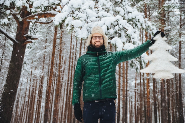 man in fur cap with ear flaps holding a tree