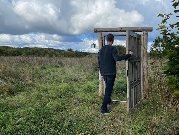 Foto man gaat door oud mysterieportaal in het open veld persoon en de deur die nergens heen leidt