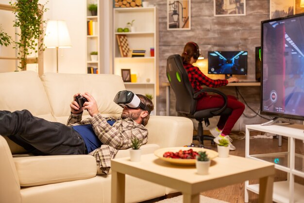 Man gamer die een VR-headset gebruikt om 's avonds laat videogames te spelen in de woonkamer