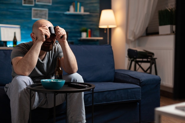 Man gamer playing sport video games with controller sitting on couch in living room