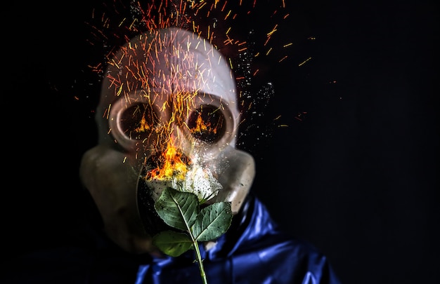 Man in the gas mask holding a burning flower. Radiation influence. Environmental pollution. Chernobyl concept. Dangerous nuclear power.