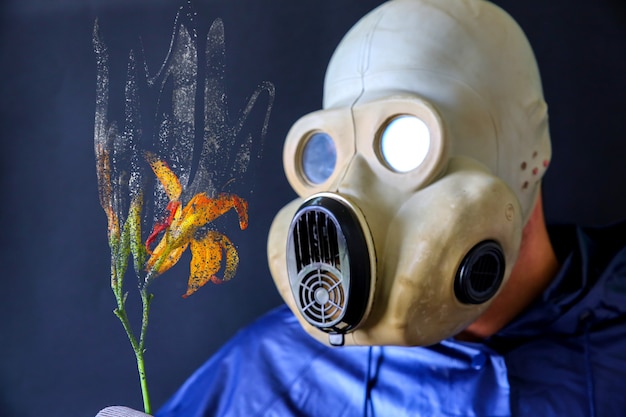 Uomo con la maschera antigas che tiene in mano un fiore in fiamme. influenza delle radiazioni. inquinamento ambientale. concetto di chernobyl. energia nucleare pericolosa.