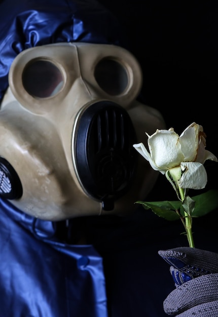 花を保持しているガスマスクの男。放射線の影響。環境汚染。チェルノブイリの概念。危険な原子力発電。生態学的災害。