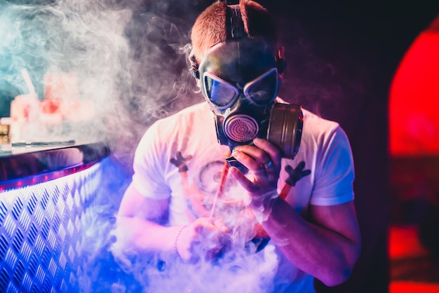 Man in a gas mask Smoking a hookah and blowing smoke