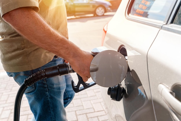 man at gas station filling tank of car with diesel to top level as fuel prices is going up