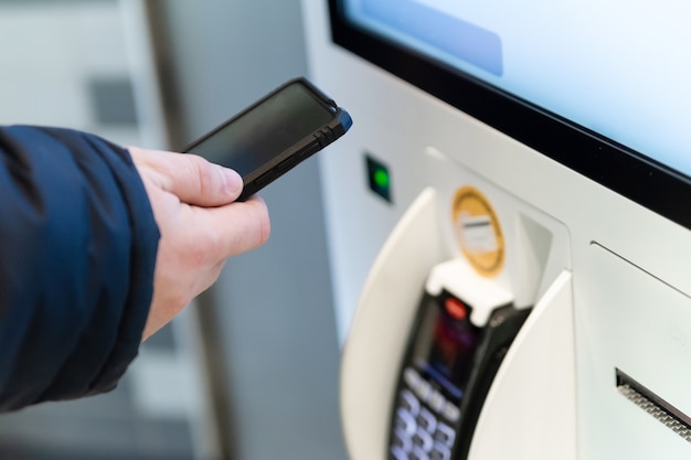 Man gebruikt een nfc-betaling in de buurt van een zelfbedieningsterminal. Paypass, telefonisch contactloos betalen.