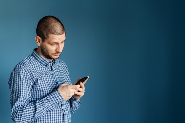 Foto man gebruikt mobiele telefoon tegen blauwe achtergrond