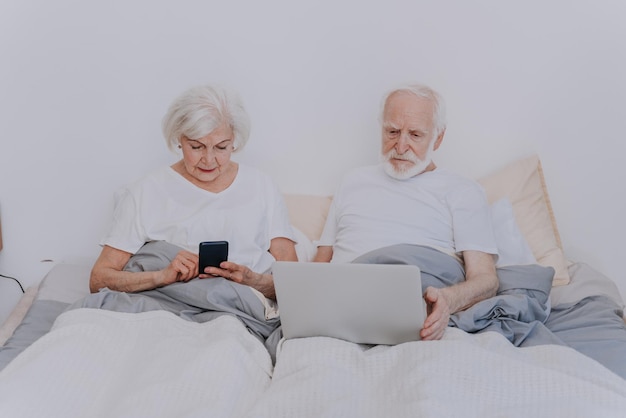 Man gebruikt mobiele telefoon terwijl hij op bed zit