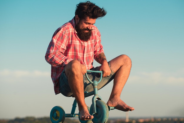 Man gedraagt zich als een kind Grappige man op een fiets Emotionele gekke man op een kinderfiets