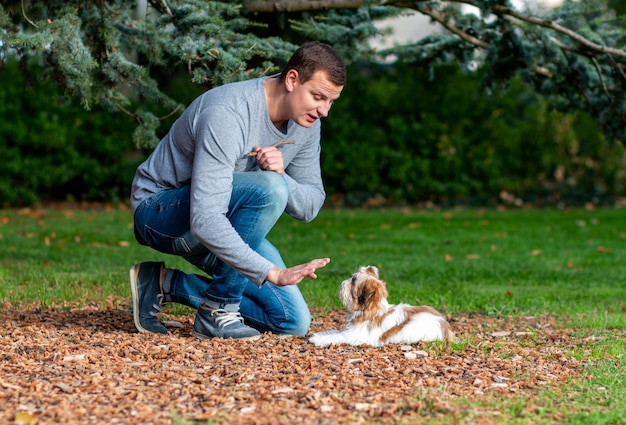 man geeft commando's aan een hond, traint een puppy buitenshuis