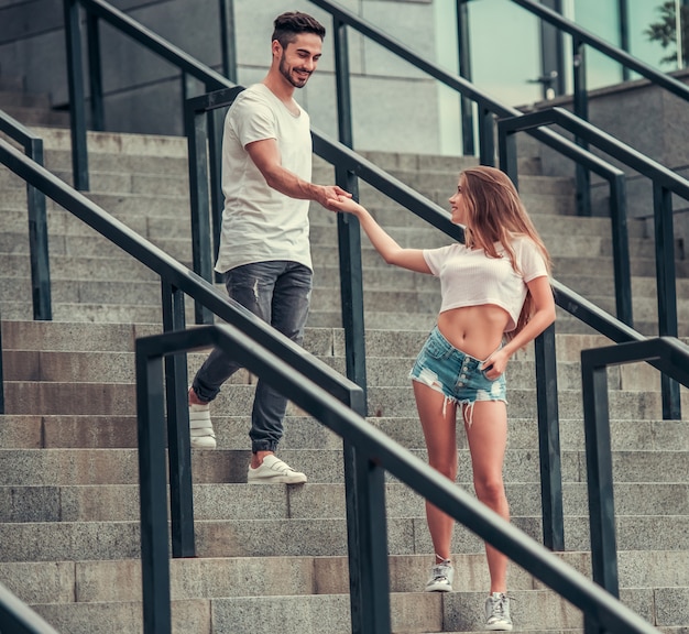 man geeft hand aan meisje terwijl ze op trappen staat. Jong koppel buiten lopen samen.