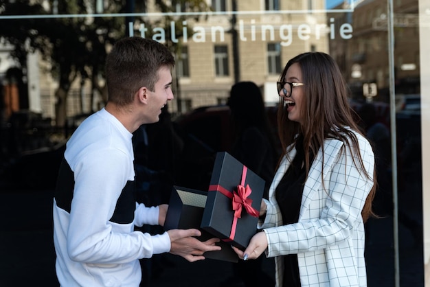Man geeft mooie brunette cadeau Jong gelukkig stel met geschenkdoos