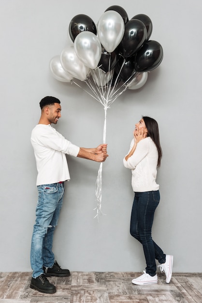 Foto man geeft vrouw veel ballonnen.