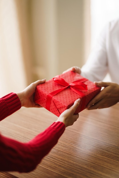 Man geeft zijn vrouw een geschenkdoos met rood lint Hands of man geeft een verrassingsgeschenkdoos voor meisje