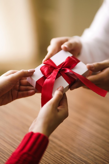 Man geeft zijn vrouw een geschenkdoos met rood lint Hands of man geeft een verrassingsgeschenkdoos voor meisje