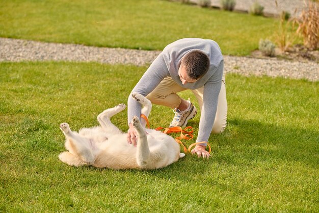 Man gehurkt spelen met hond liggend op zijn rug