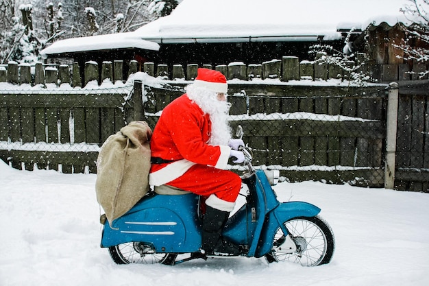 Man gekleed in een kerstman kostuum op een motorfiets op de sneeuw