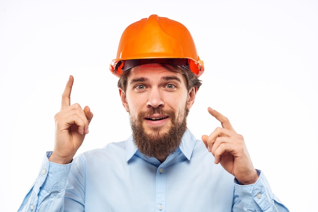 男性が手でエンジニアのオレンジ色のヘルメットの安全構造をジェスチャーする