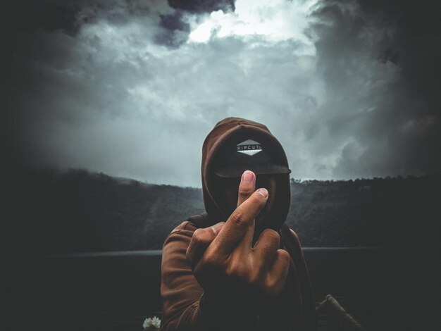 Photo man gesturing against cloudy sky