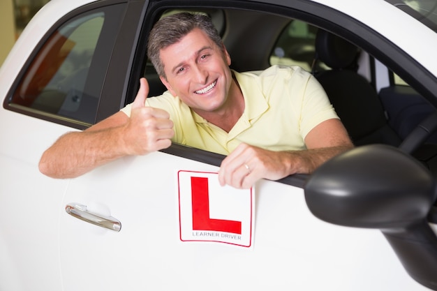 Foto equipaggi gesturing i pollici su che tengono un segno del driver del principiante