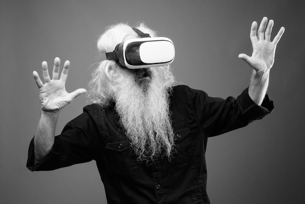 Foto uomo che fa gesti indossando un simulatore di realtà virtuale sullo sfondo grigio