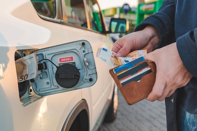男は財布からユーロを取得し、車のタンクのガソリン価格に入れます
