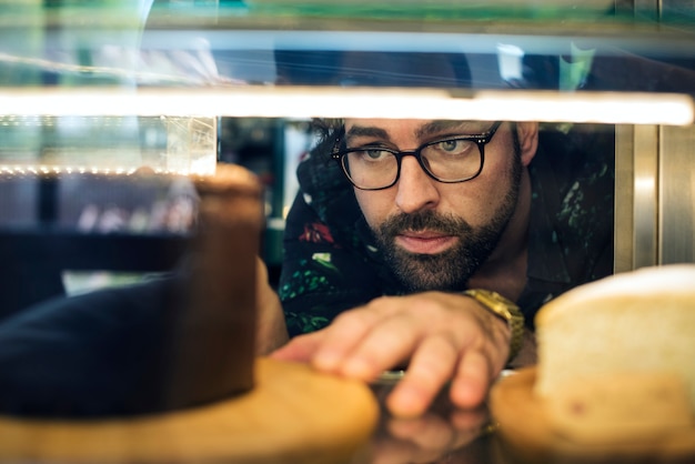 Man getting cake out of the display fridge