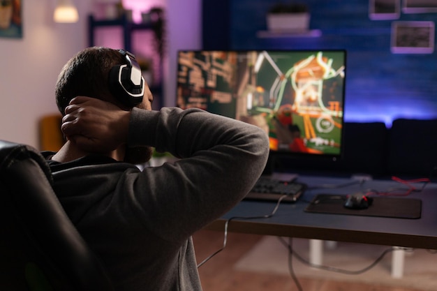 Person playing video games with controller on computer. Player using  joystick and wearing headphones to play online game on monitor. Modern man  using gaming equipment to have fun. Stock Photo