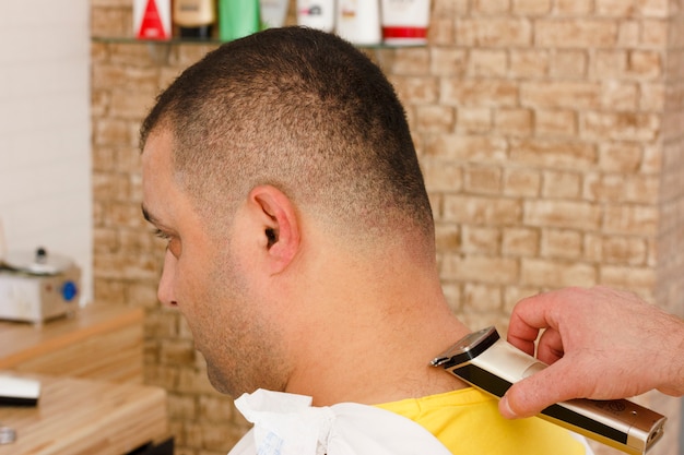 Man getting short hait trimming at a barber shop with clipper machine