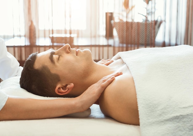 Man getting shoulders massage in spa centre