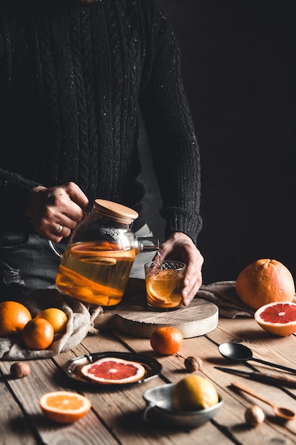 Man giet citrus thee op een houten tafel