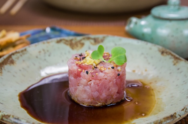 Foto man giet sojasaus in tonijn tartaar verrukking in een mooi versierd bord