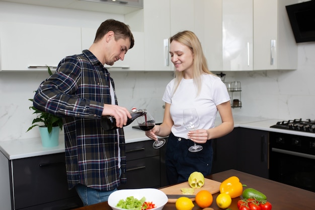 Man gieten een glas wijn voor zijn gelukkige vrouw in de keuken