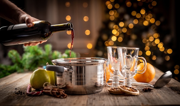 Man gieten rode wijn uit de fles in de pot om te verwarmen en warme aromatische drank te bereiden