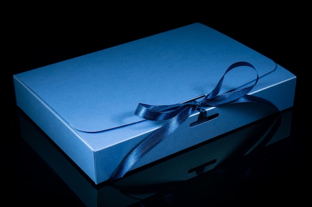 Фото Концепция подарка человека подарочная коробка с роскошным бантом на темном фоне горизонтальный с копировальным пространством