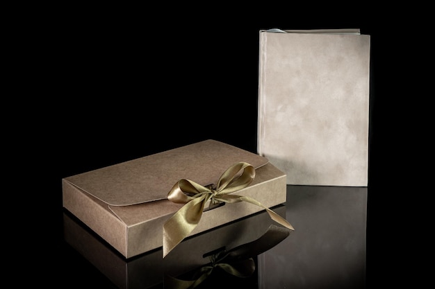 写真 プレゼントボックス: クラフトペーパーに包まれて黒い背景の豪華なボウでコピースペースで水平に