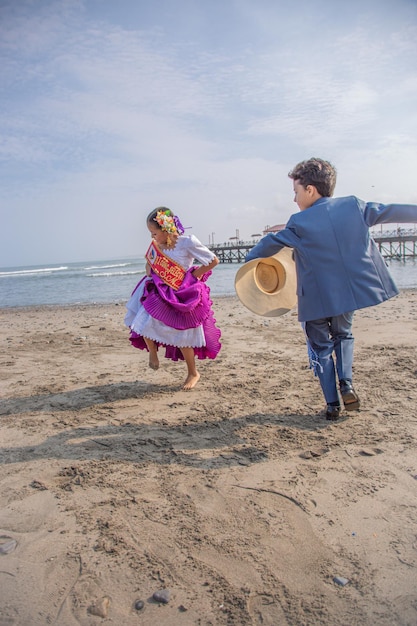 a man and a girl are running on the beach and the girl is wearing a dress that says