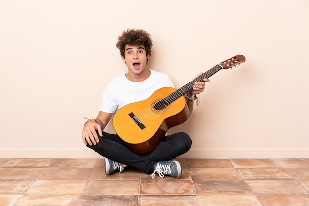 man gitaar spelen en op de vloer zitten