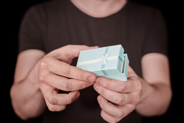 Man give a gift in gift box. Opening Valentine gift. Small anniversary giftbox from man. Little surprise concept. Black background.