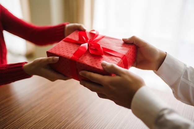 Man gives to his woman a gift box with red ribbon Hands of man gives surprise gift box for girl